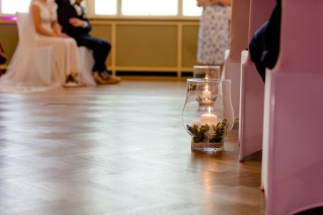 Hochzeitszeremonie mit Brautpaar und beleuchteten Kerzen im Raum.