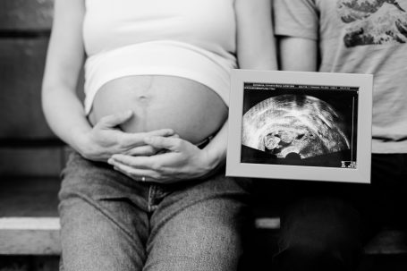 Schwangere Person mit Ultraschallbild des Babys.