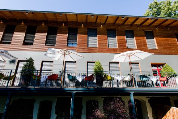 Terrasse eines Gebäudes mit Sonnenschirmen und bunten Möbeln.