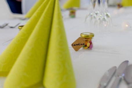 Gelbe Servietten auf einem Tisch mit Gläsern und dekorativen Mini-Gläsern.