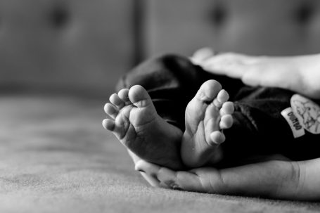 Ein Erwachsener hält die Füße eines Babys sanft im Schoß.