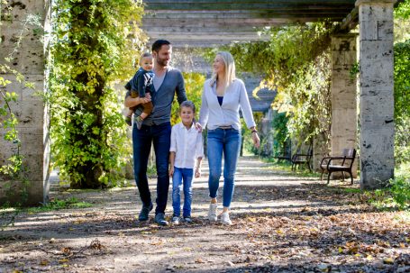 Familie mit zwei Kindern spaziert durch einen herbstlichen Park.