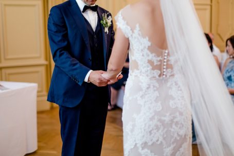 Braut und Bräutigam halten sich während der Zeremonie die Hände. Elegante Hochzeitskleidung.