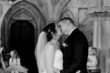 Braut und Bräutigam küssen sich in einer historischen Location während der Hochzeit.