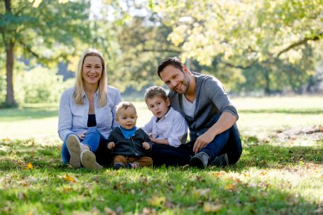 Familienporträt im Freien mit zwei Kindern und Eltern auf einer Wiese.