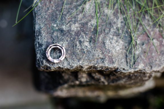Silberner Ring liegt auf einem grauen, strukturierten Stein.