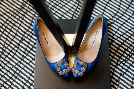 Blaue Schuhe mit glitzerndem Schmuckdetail auf einem schwarzen Grund.