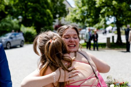 Zwei Frauen umarmen sich herzlich auf einer Feier im Freien.