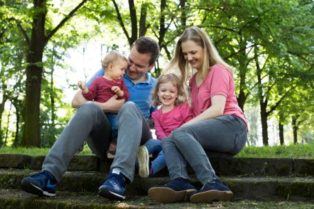 Eine Familie sitzt im Freien auf einer Treppe und verbringt Zeit miteinander.