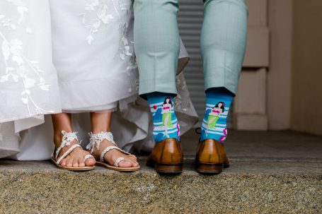 Brautschuhe und bunte Socken des Bräutigams, stehen nebeneinander auf der Treppe.