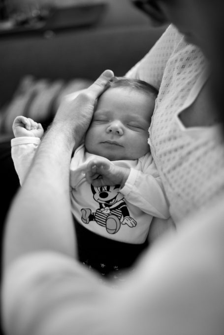 Schlafendes Baby in den Armen eines Erwachsenen, sanfte Zärtlichkeit.