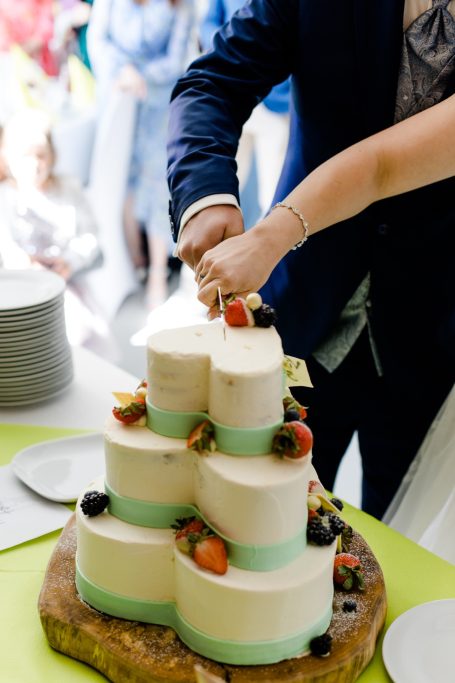 Eine mehrstöckige Torte mit Früchten wird angeschnitten.