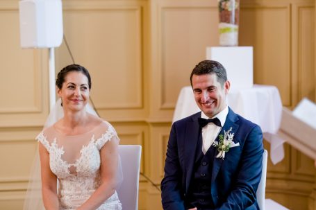 Braut und Bräutigam sitzen lächelnd nebeneinander bei der Hochzeit.