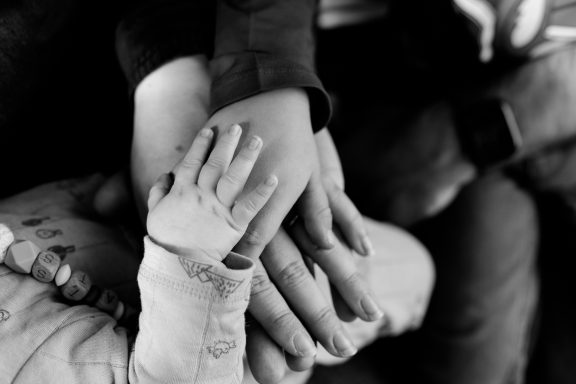 Hände von Erwachsenen und Kindern, die übereinander gelegt sind, in Schwarz-Weiß.